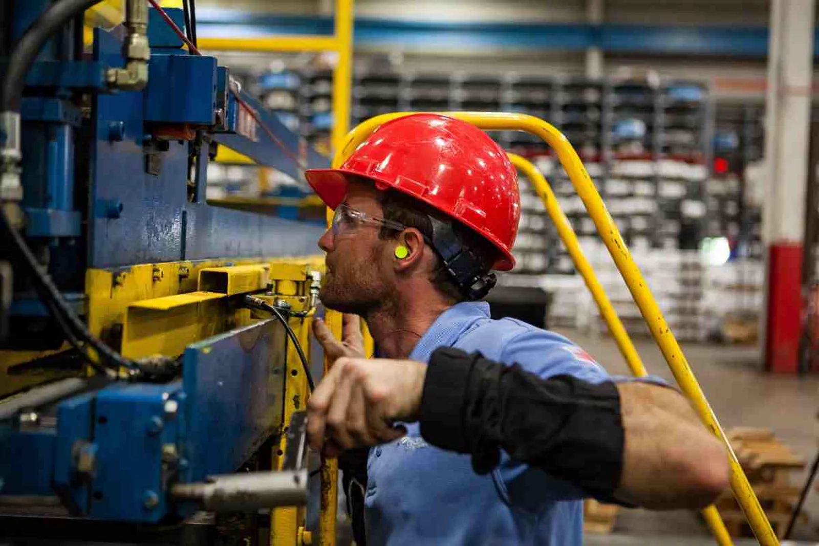 Shop floor operator in a hard hat adjusting manufacturing equipment controls